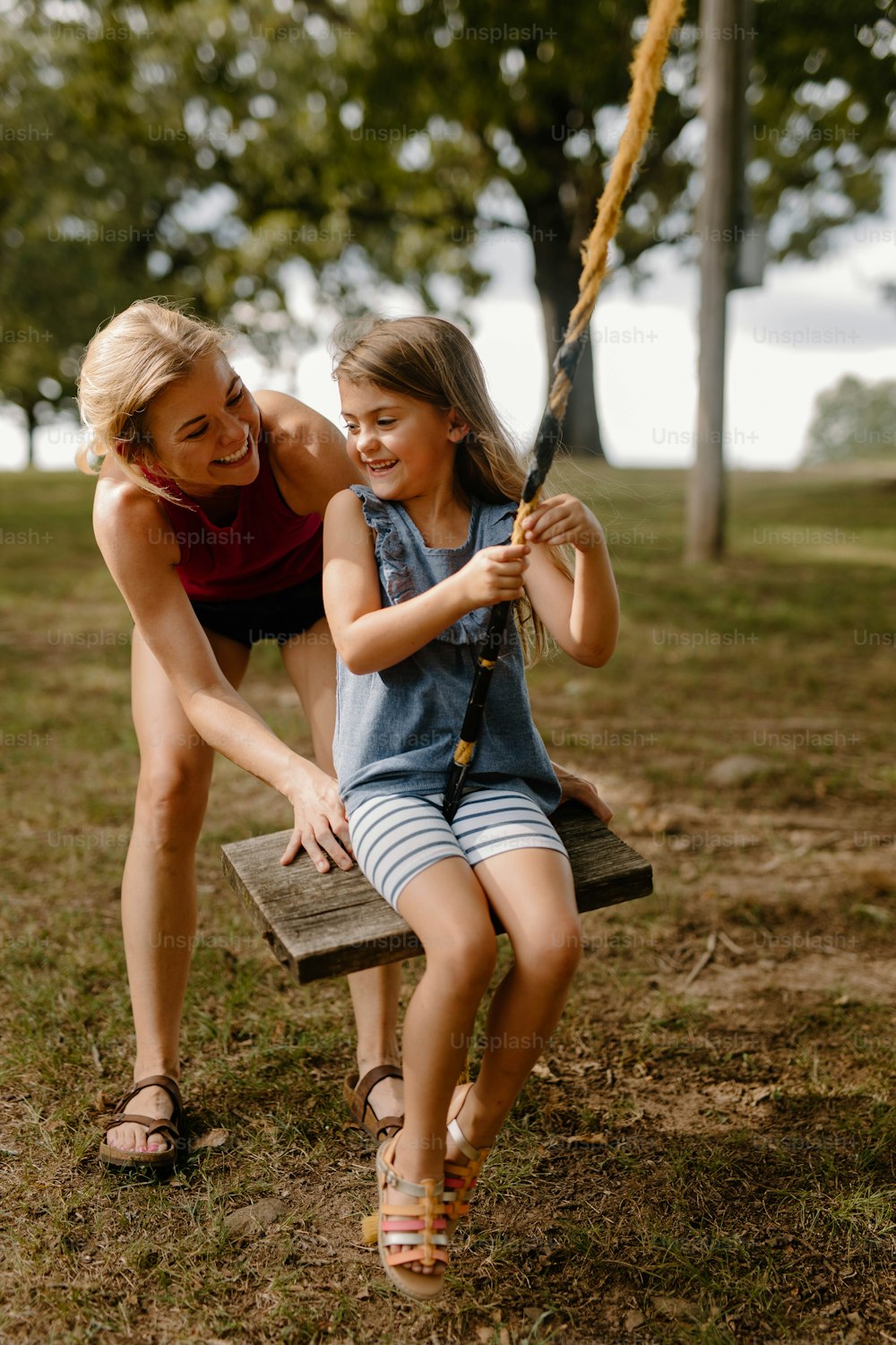 a woman and a little girl sitting on a swing