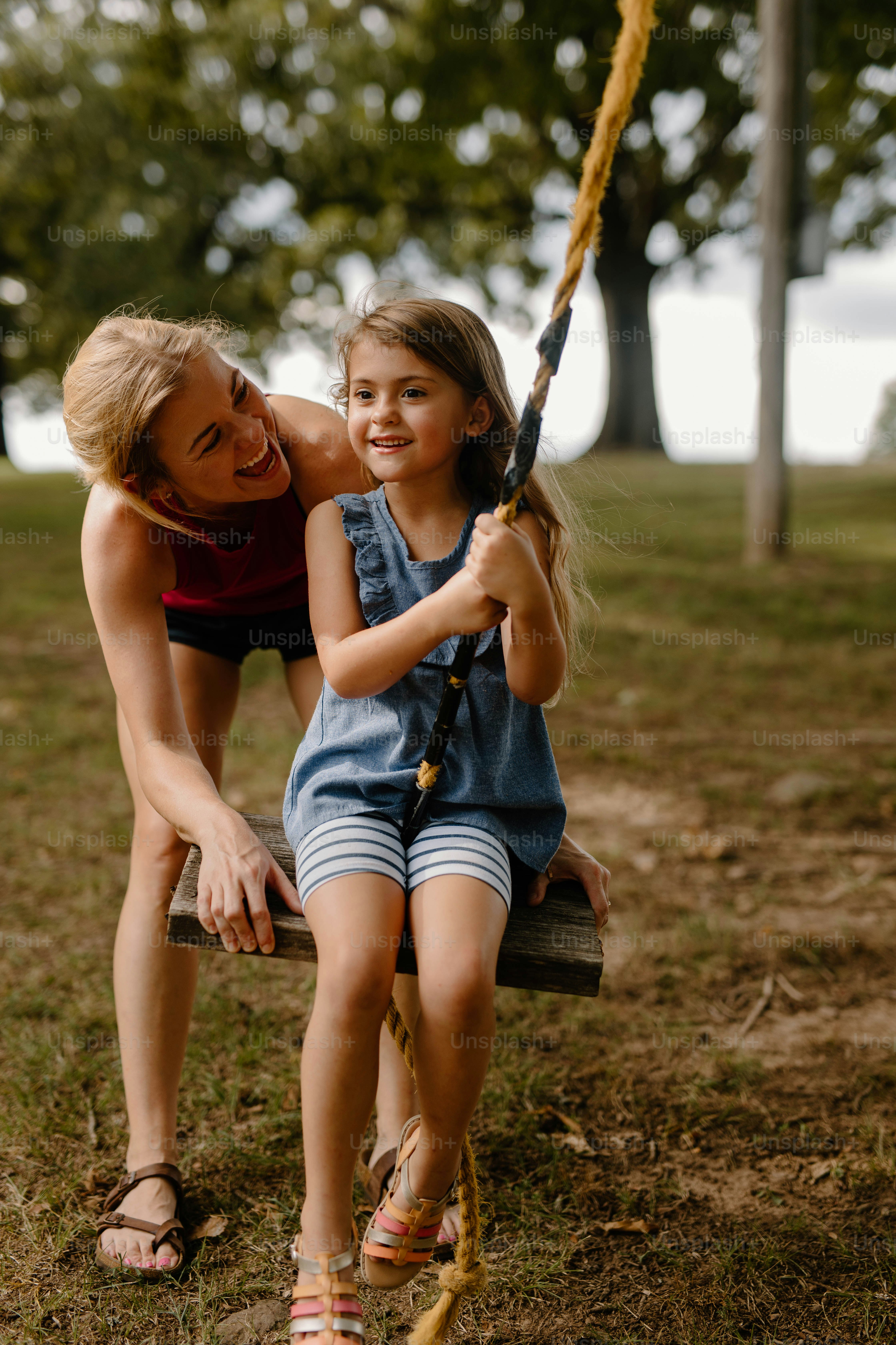 a woman and a little girl sitting on a swing