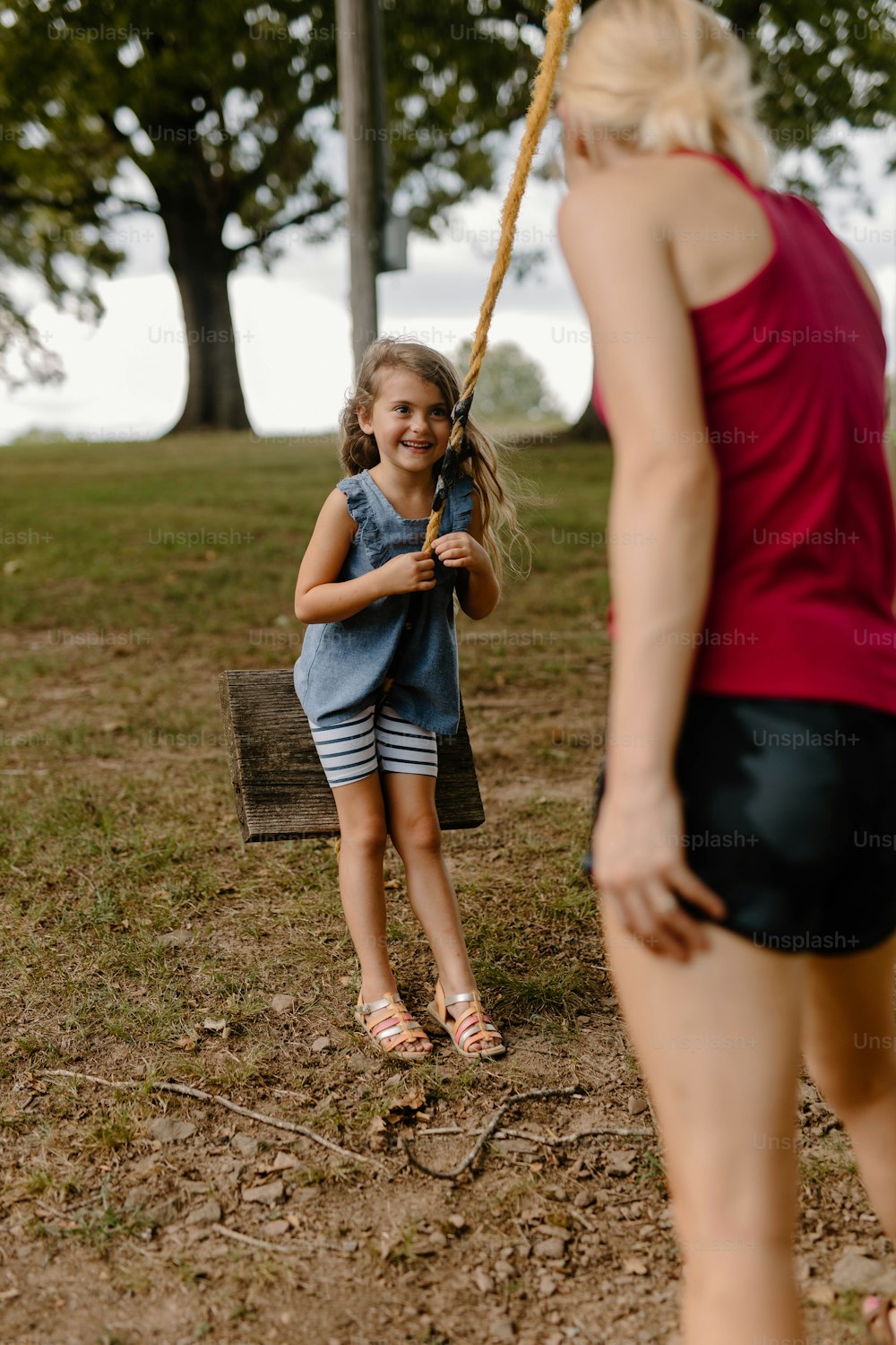 Une petite fille tenant une batte de baseball à côté d’une femme