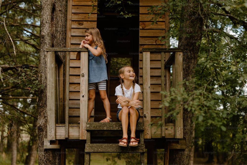 two little girls sitting on a tree house