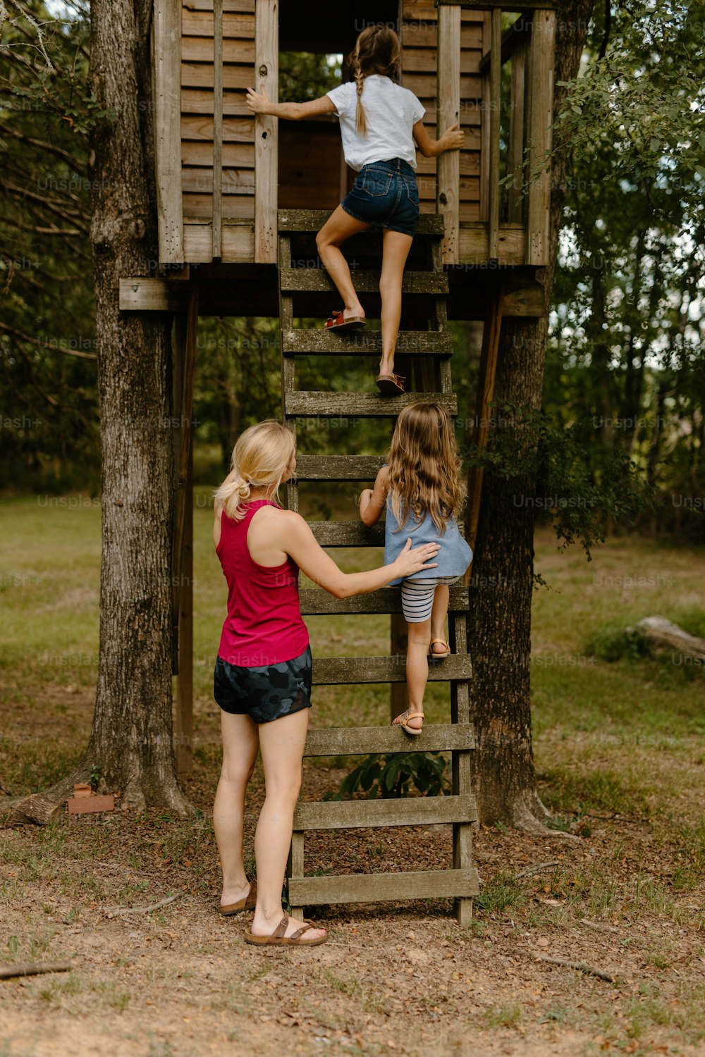 Un grupo de chicas trepando a una casa de árbol de madera