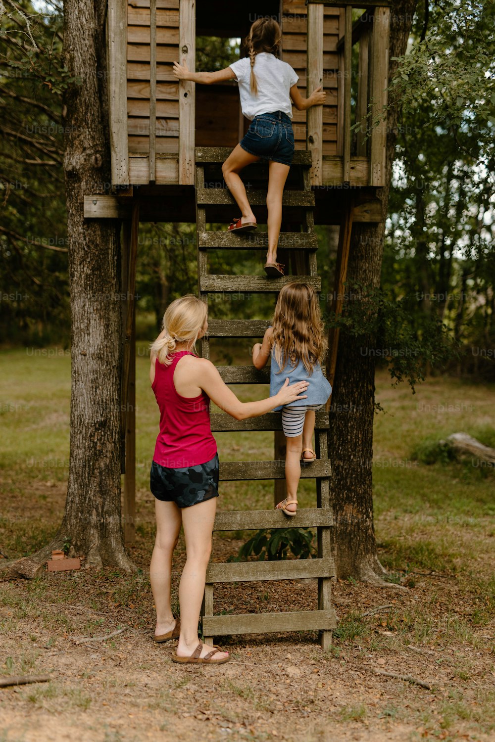 a group of girls climbing a wooden tree house
