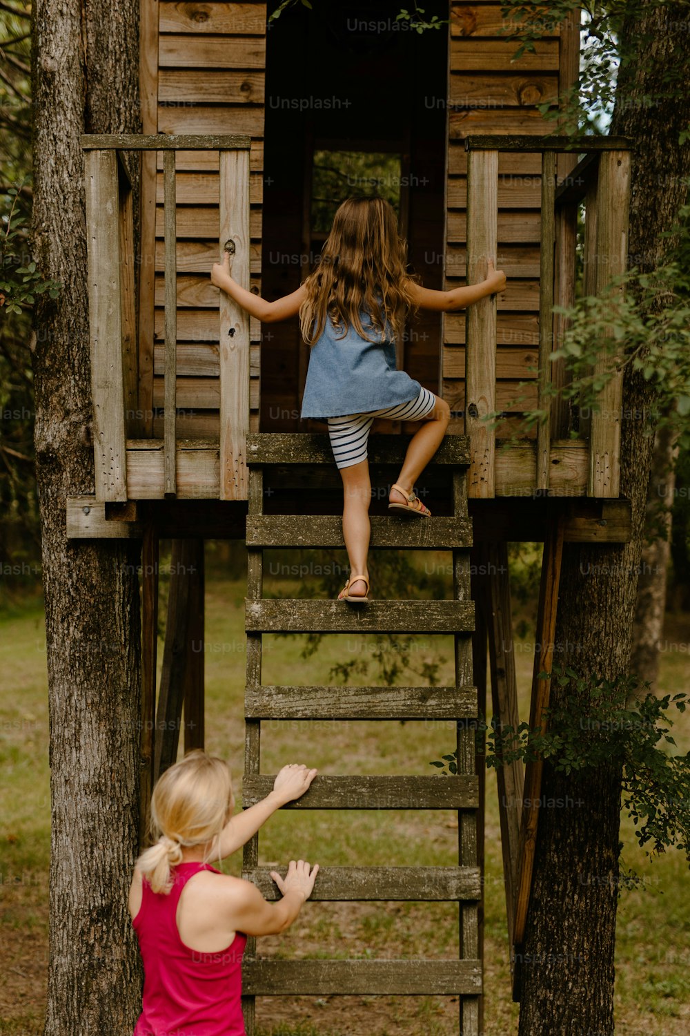 a little girl standing on top of a wooden tree house