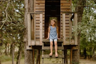 Ein kleines Mädchen, das auf einem hölzernen Baumhaus sitzt