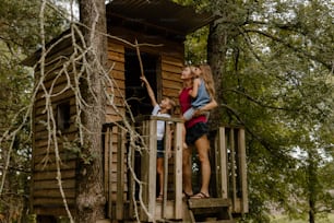 a woman and a child standing on a tree house