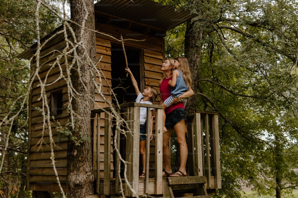 uma mulher e uma criança em pé em uma casa na árvore