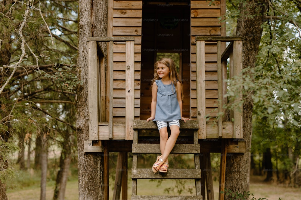 나무 위의 집에 앉아 있는 어린 소녀