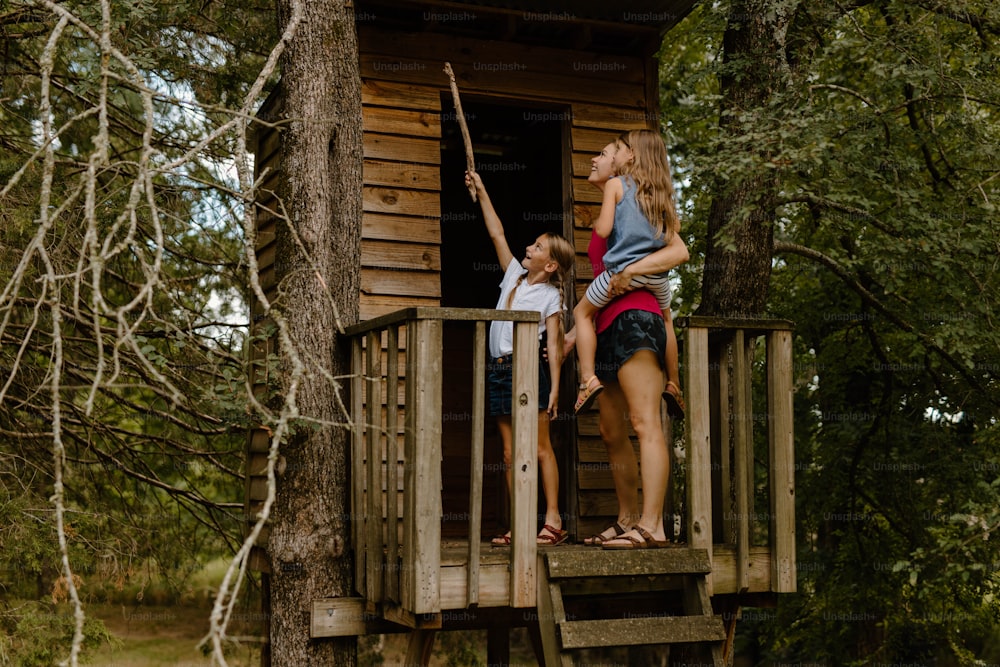 Une femme et deux enfants dans une cabane dans les arbres