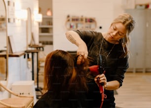 Eine Frau föhnt die Haare einer anderen Frau in einem Salon