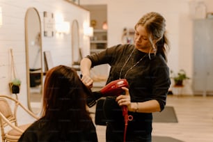 a woman is blow drying another woman's hair