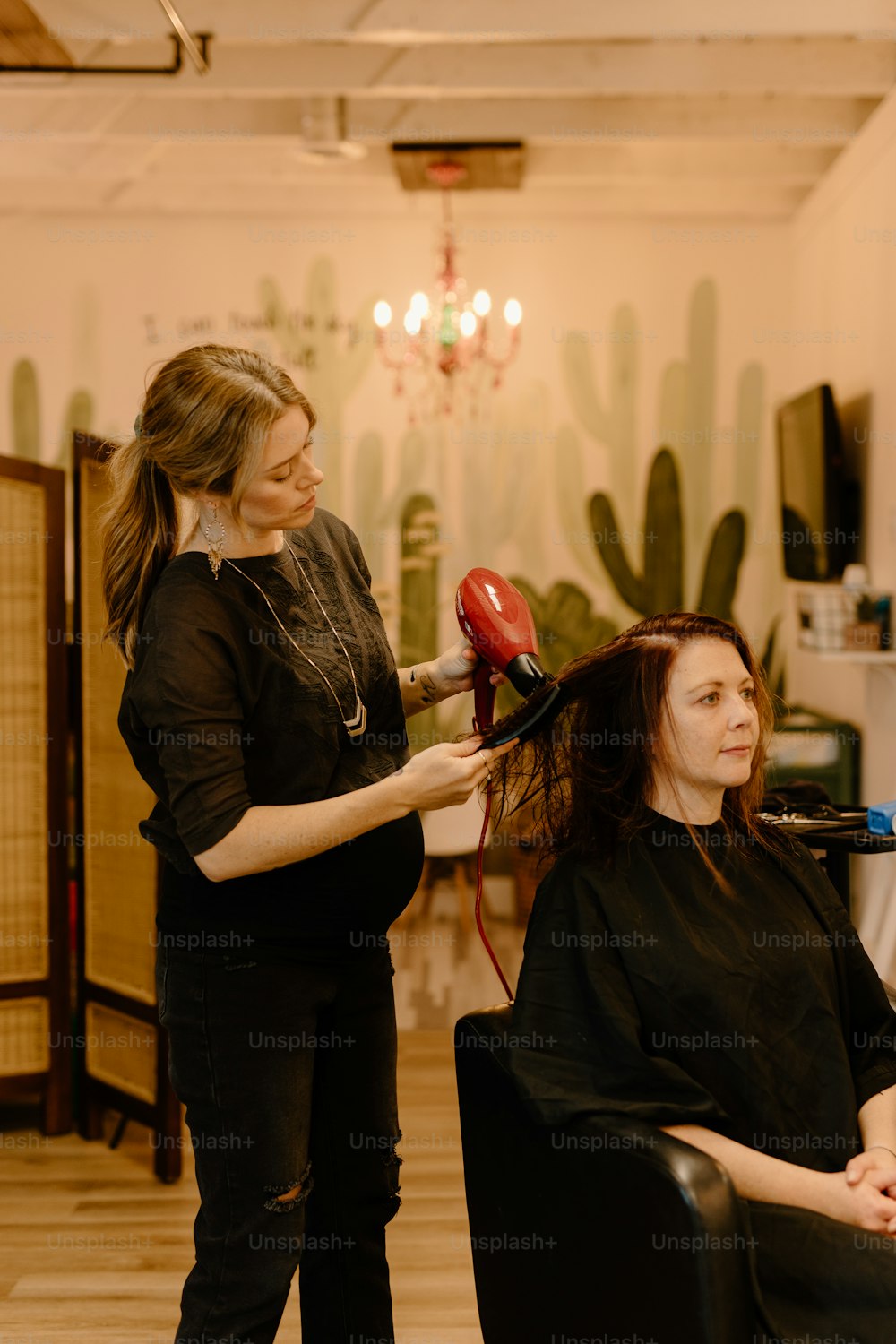 Une femme sèche les cheveux d’une autre femme dans un salon