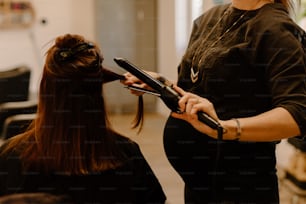 a woman is blow drying her hair in a salon