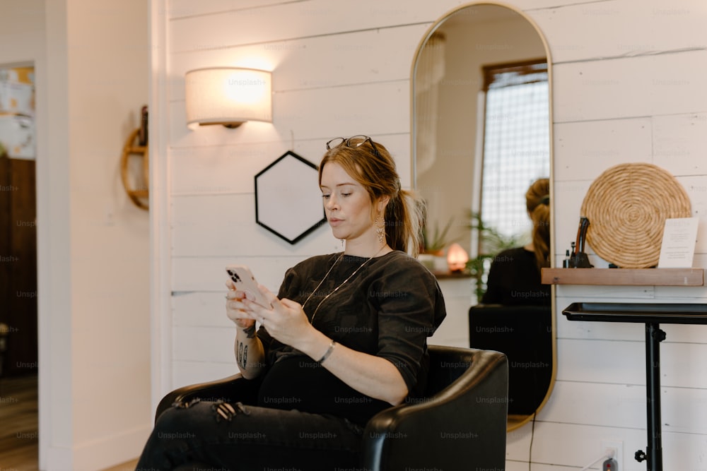 a woman sitting in a chair looking at her cell phone