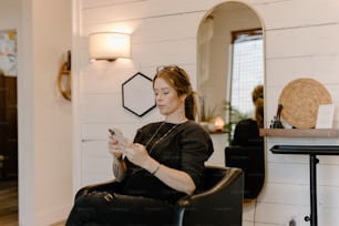 Una donna seduta su una sedia che guarda il suo cellulare
