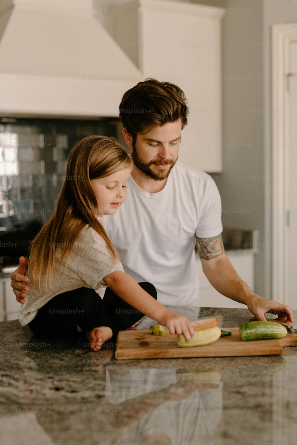 Un hombre y una niña cortando verduras en una tabla de cortar