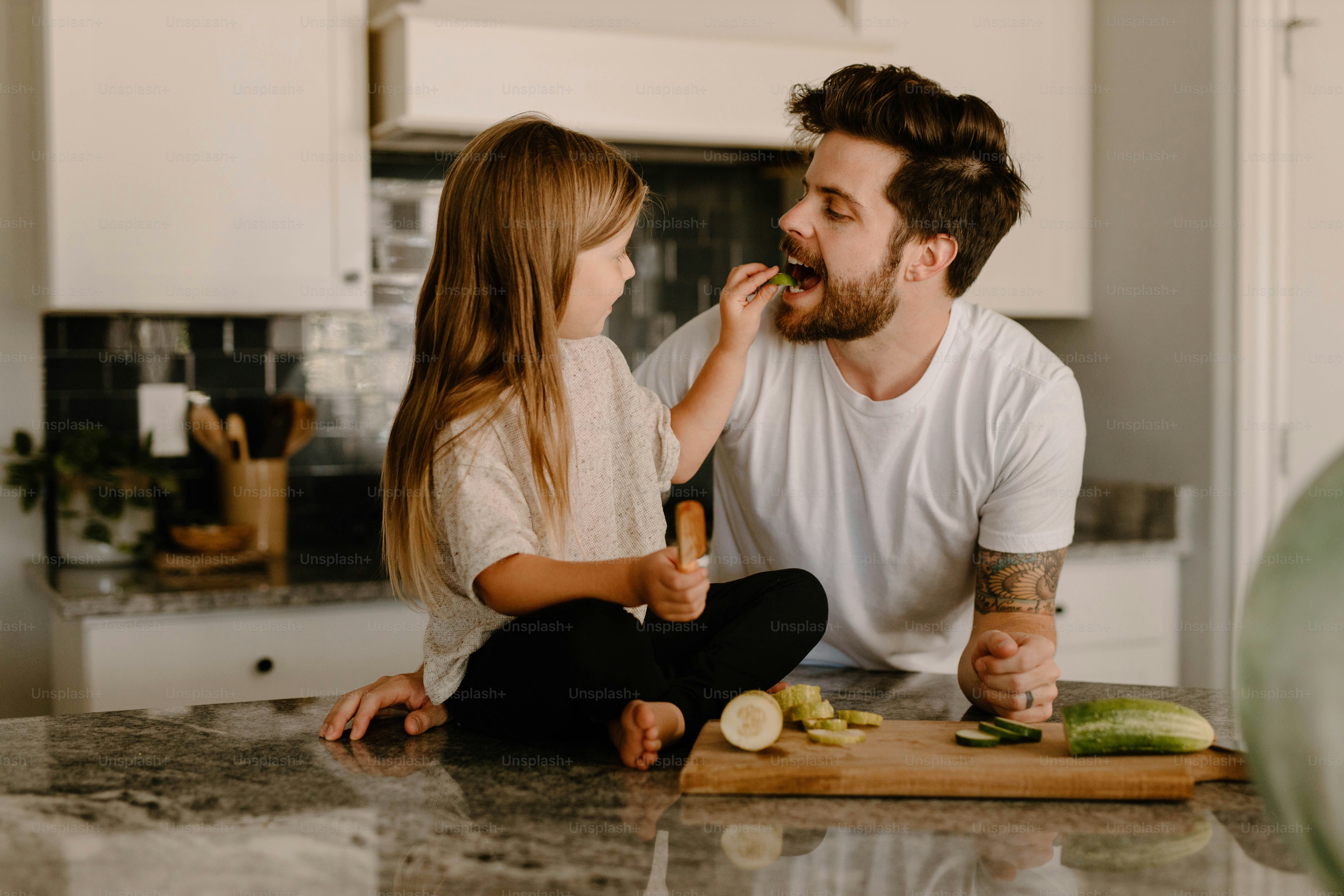 台所のカウンターに座っている男と少女