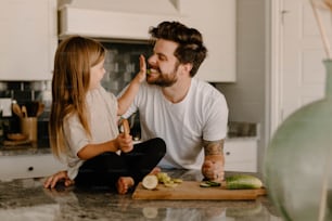 a man and a little girl sitting on a kitchen counter