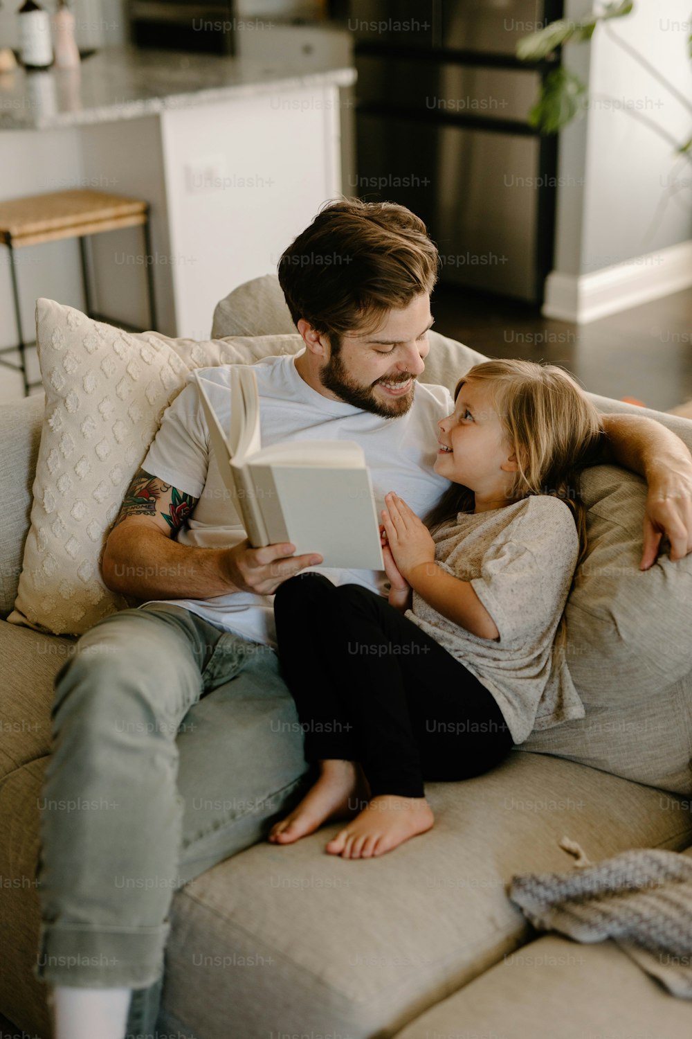 Ein Mann, der einem kleinen Mädchen auf einer Couch ein Buch vorliest