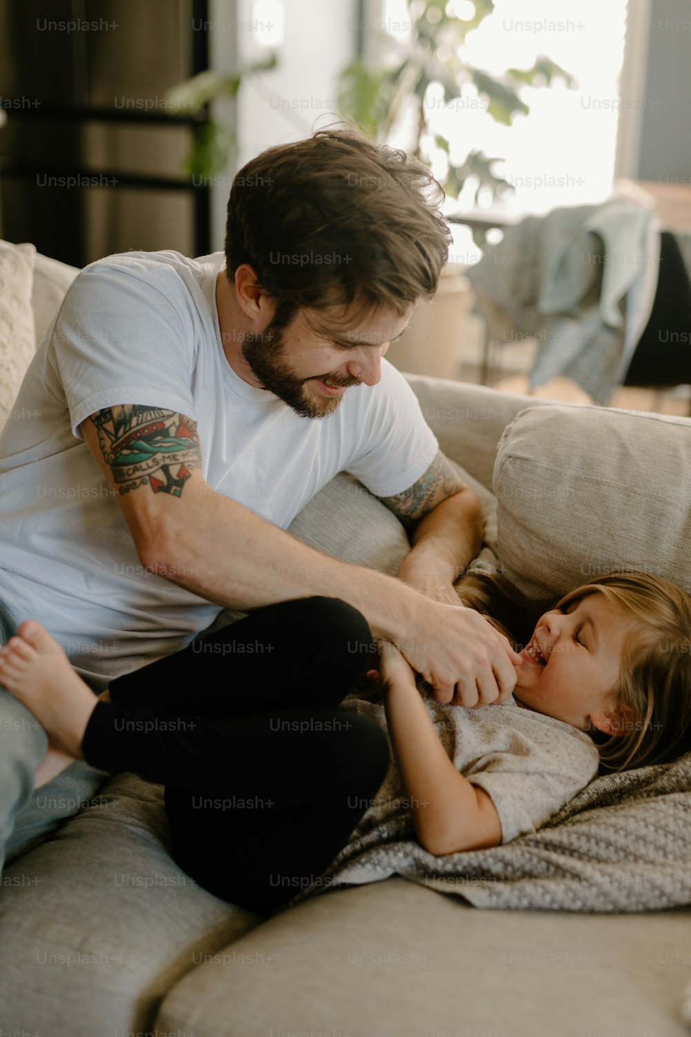 a man sitting on a couch next to a little girl