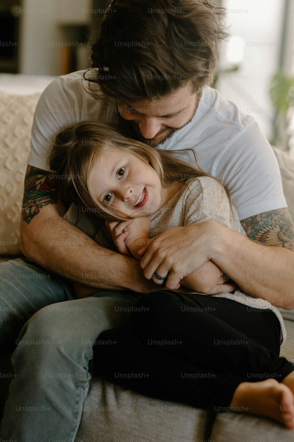 um homem abraçando uma garotinha em cima de um sofá