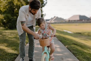 a man teaching a little girl how to ride a bike