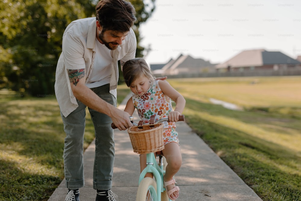 a man teaching a little girl how to ride a bike