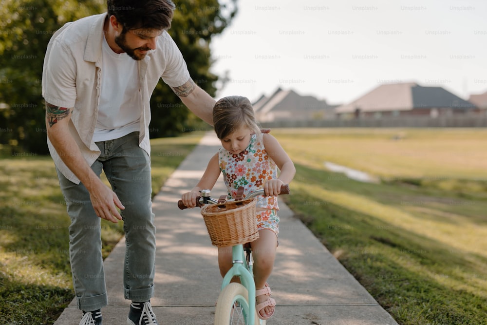 a man teaching a little girl how to ride a bike