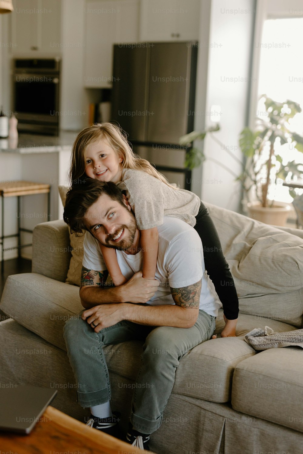 Ein Mann, der auf einer Couch sitzt und ein kleines Mädchen hält