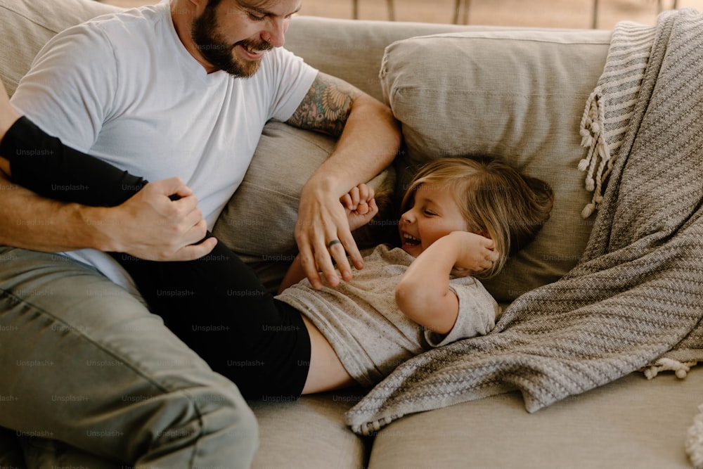 a man sitting on a couch with a little girl