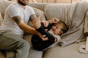 a man sitting on a couch next to a little girl