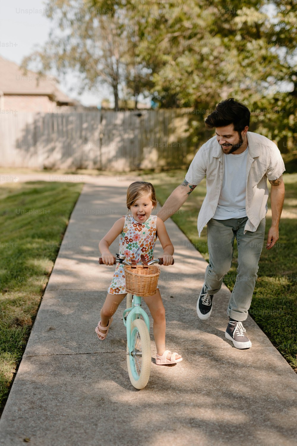 a man pushing a little girl on a tricycle