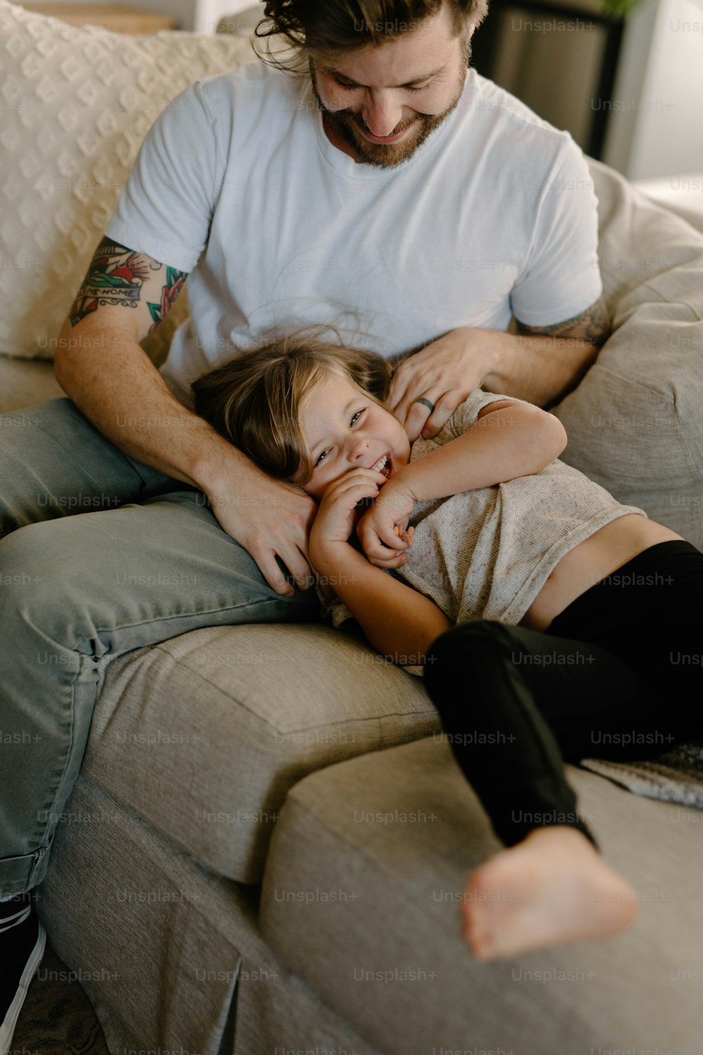 a man sitting on top of a couch next to a little girl