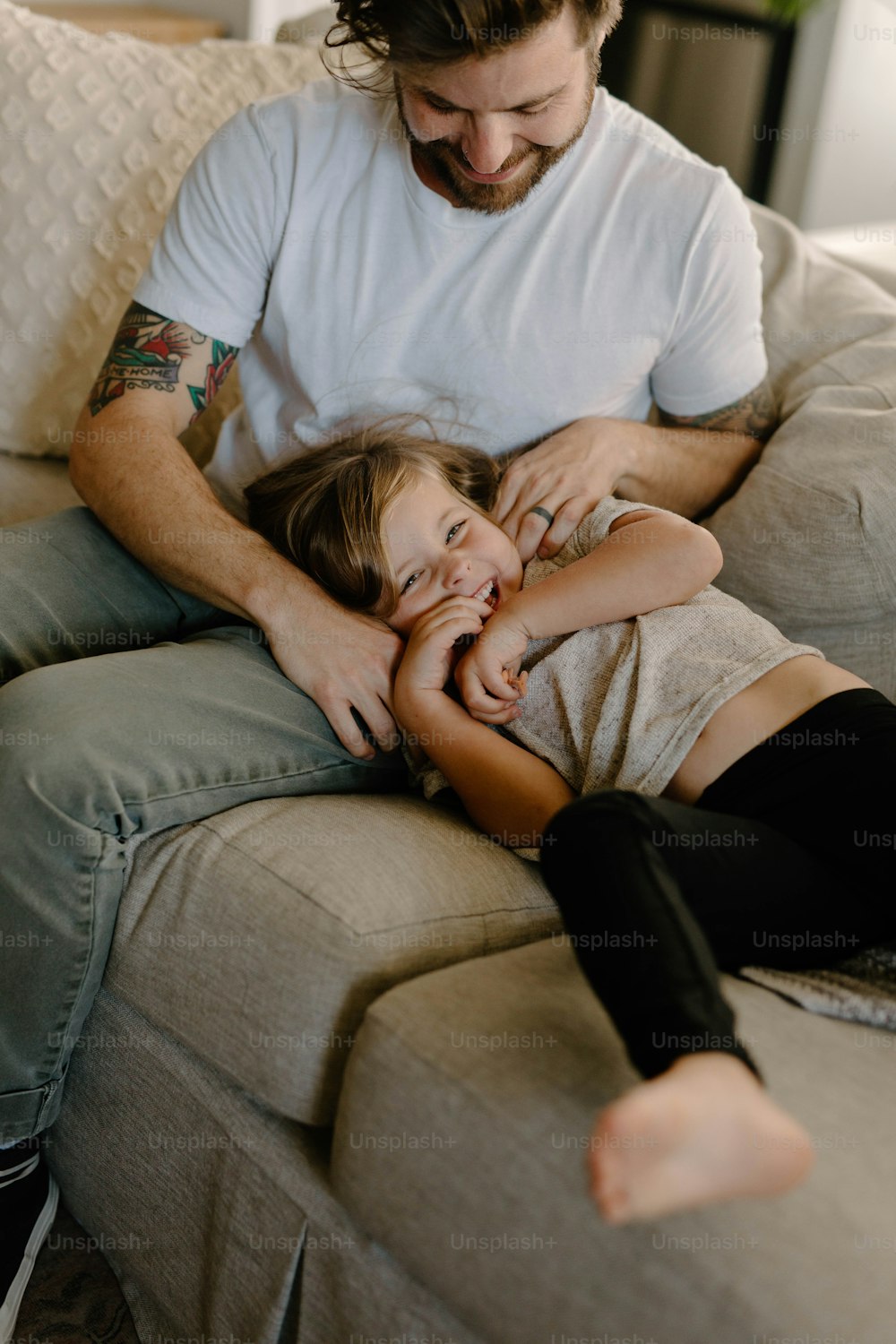 Un hombre sentado encima de un sofá junto a una niña