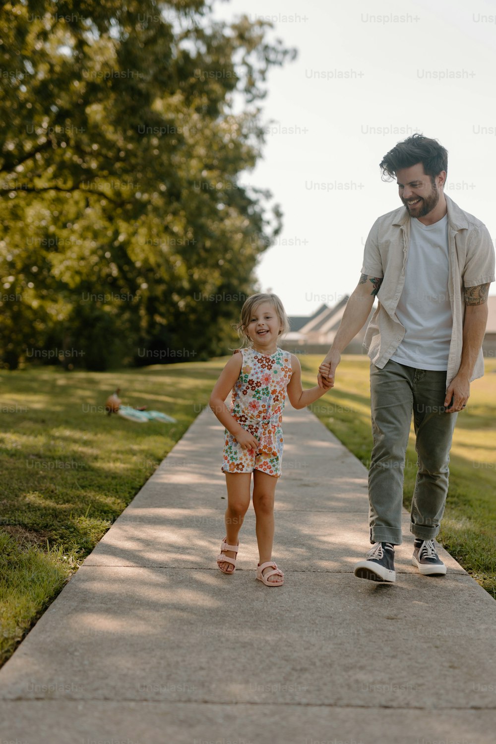 a man and a little girl walking down a sidewalk