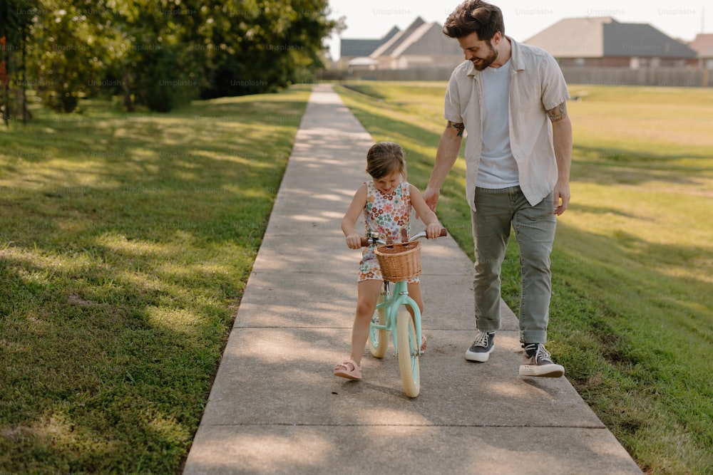 Un uomo e una bambina che vanno in bicicletta lungo un marciapiede