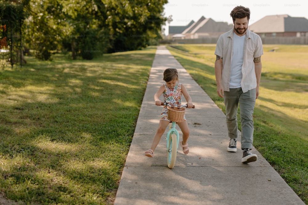 a man and a little girl riding bikes down a sidewalk