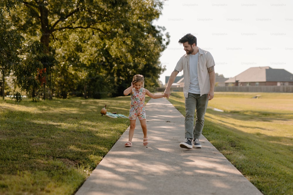 a man and a little girl walking down a sidewalk