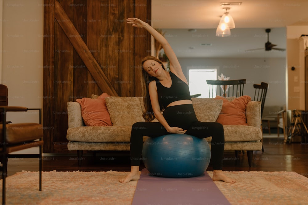 uma mulher fazendo yoga em uma bola em uma sala de estar