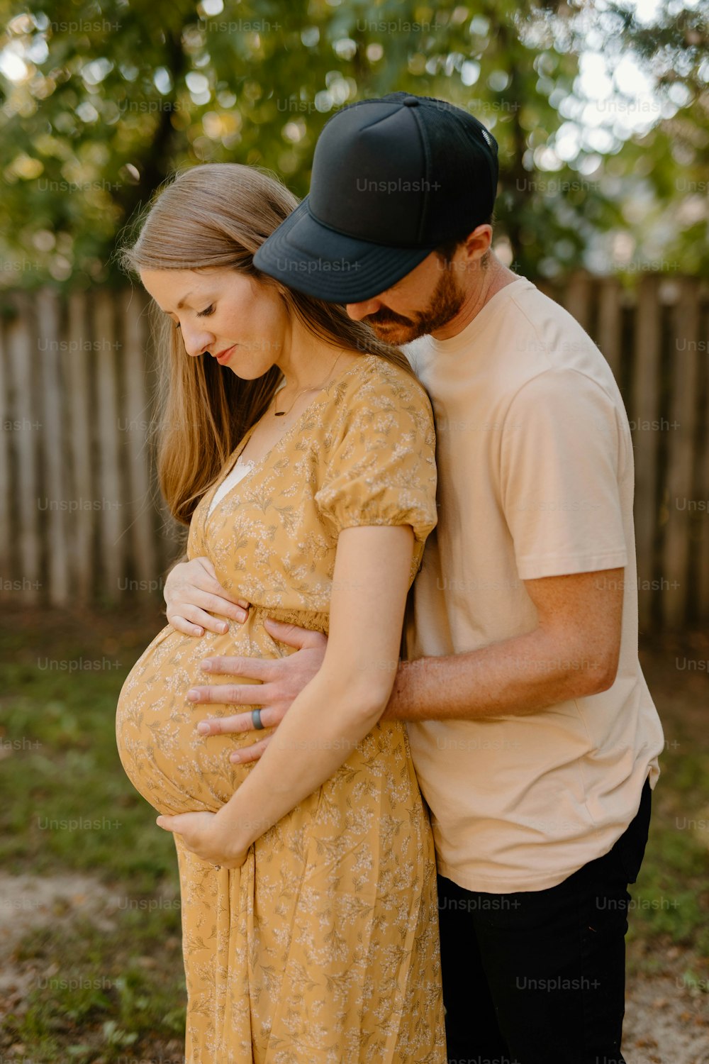 a pregnant couple cuddling in a backyard