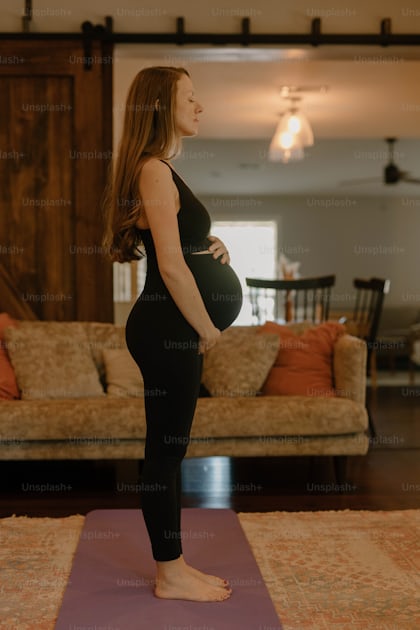 Una Joven Embarazada En Ropa Deportiva Medita Sentada Con El Vientre Sobre  Un Tapete Rosado Después De Practicar Yoga Cerca De Una Foto de archivo -  Imagen de bebé, gimnasio: 238610788