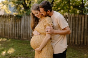 a pregnant couple embracing in a backyard