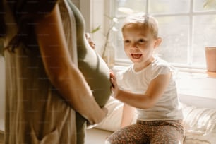 a little boy sitting on a pregnant woman's belly