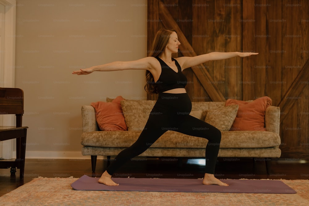 a woman doing a yoga pose in front of a couch