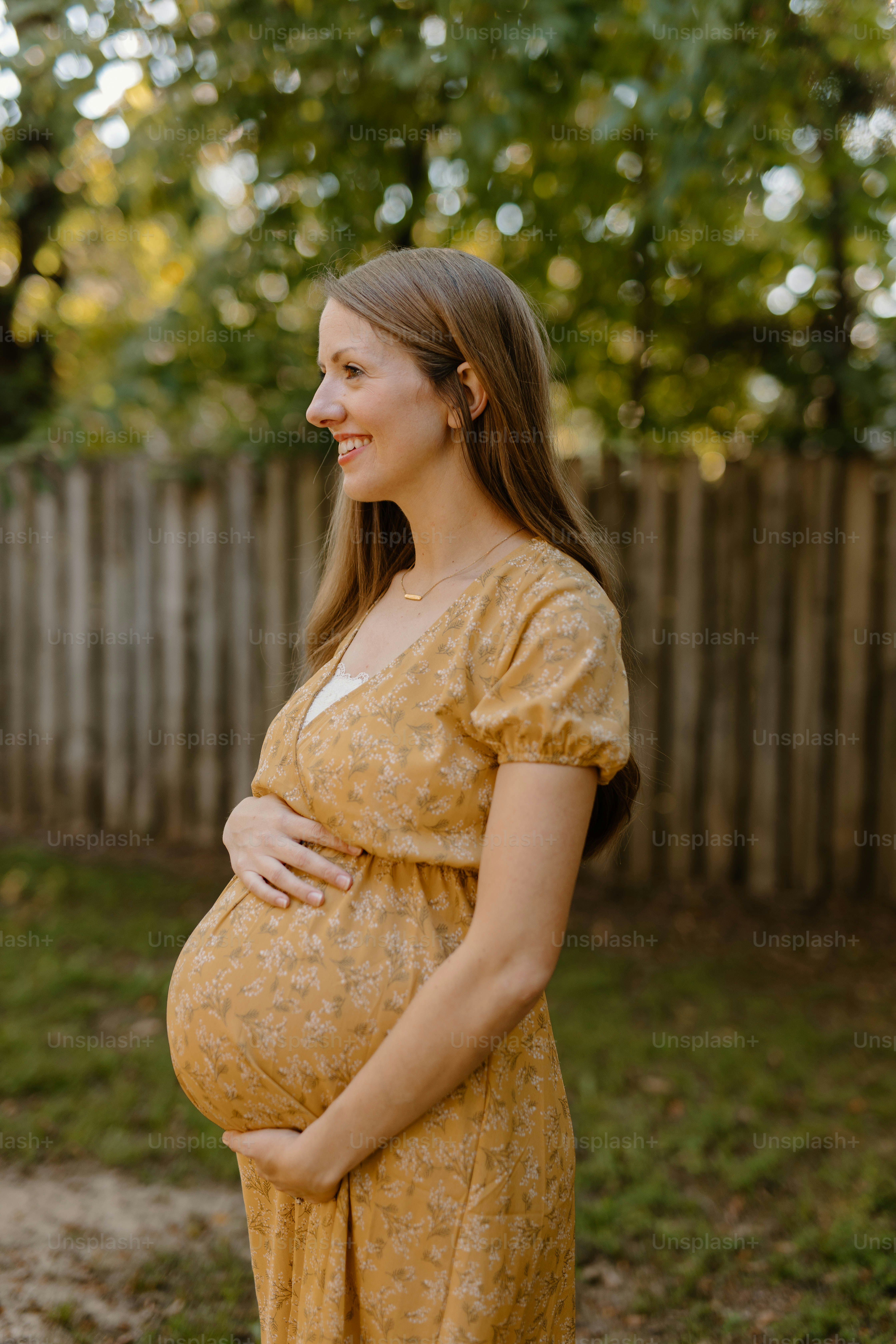 a pregnant woman in a yellow dress poses for a picture