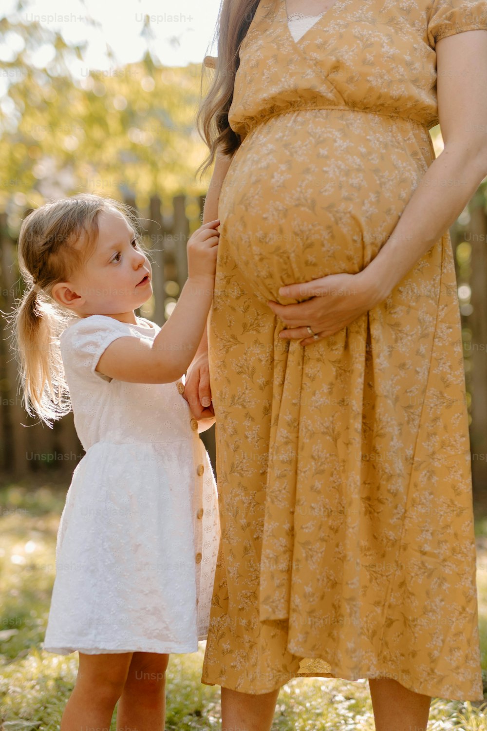 Una mujer embarazada sosteniendo la mano de una niña