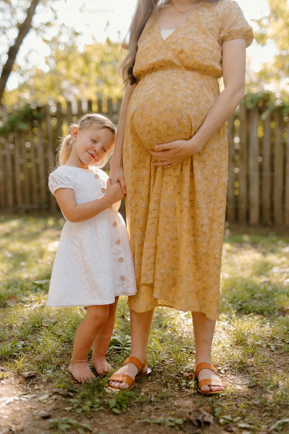 Una mujer embarazada de pie junto a una niña