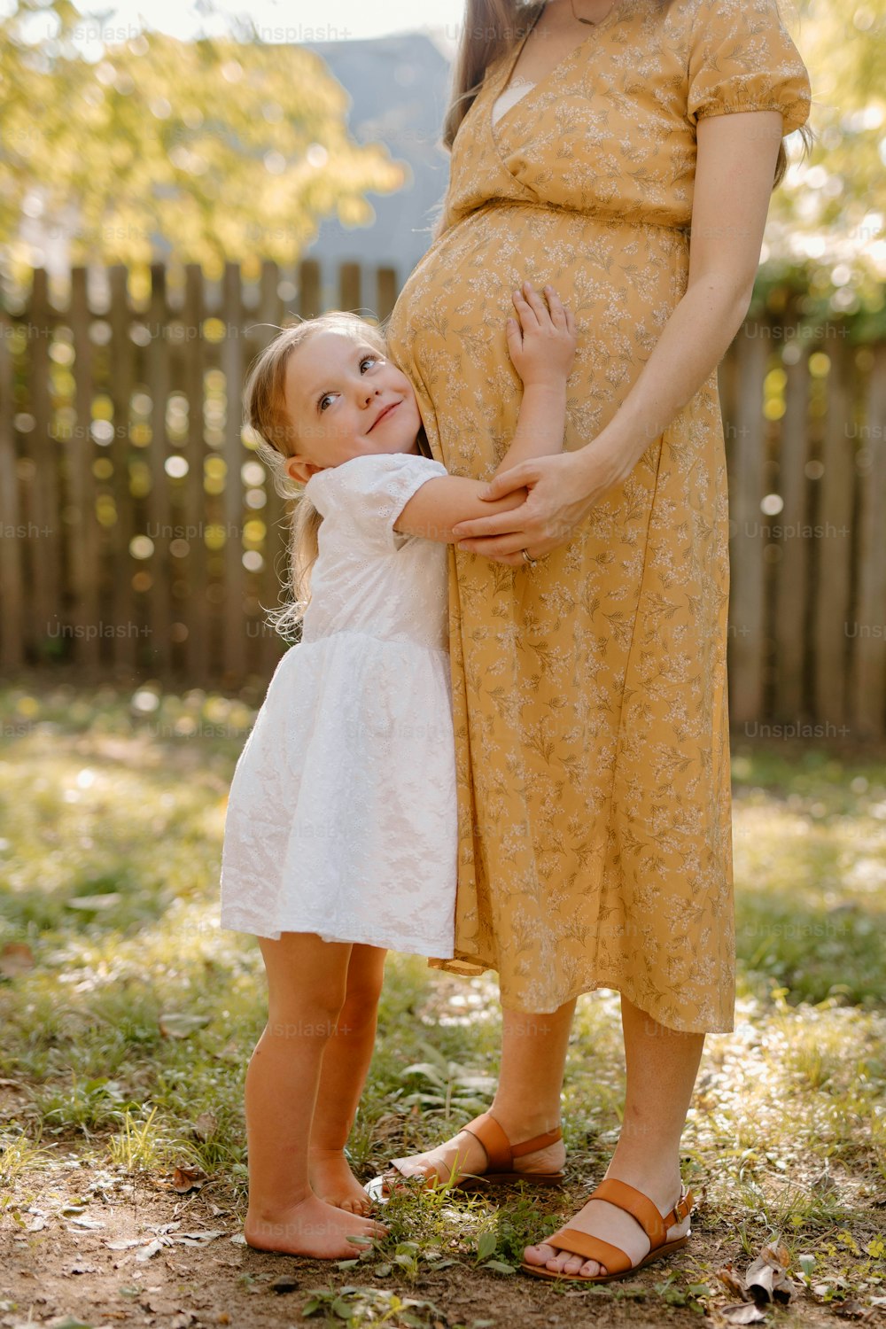 eine schwangere Frau, die ein kleines Kind im Arm hält