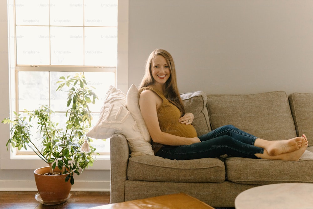 Eine Frau, die mit gekreuzten Beinen auf einer Couch sitzt