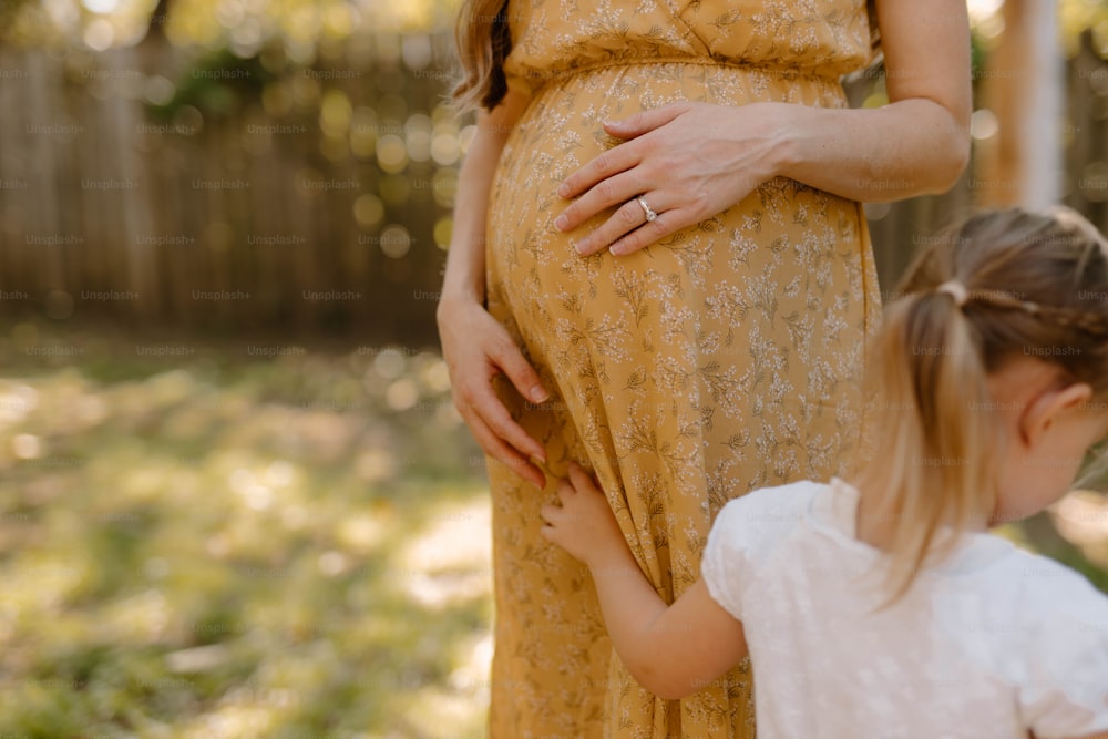 a pregnant woman holding the belly of a young girl