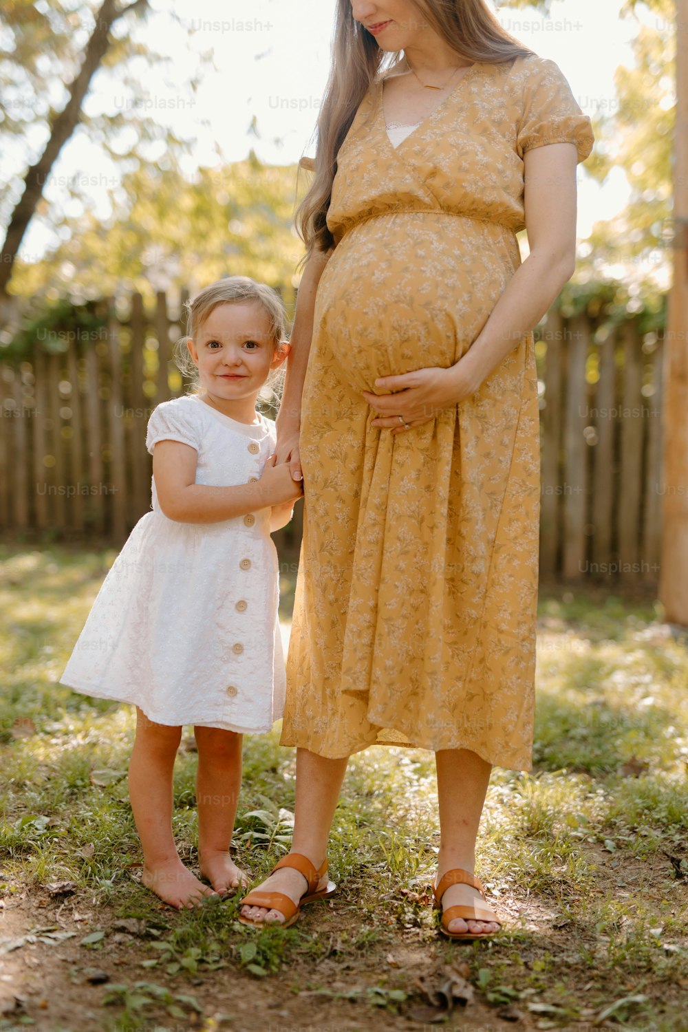 a pregnant woman standing next to a little girl